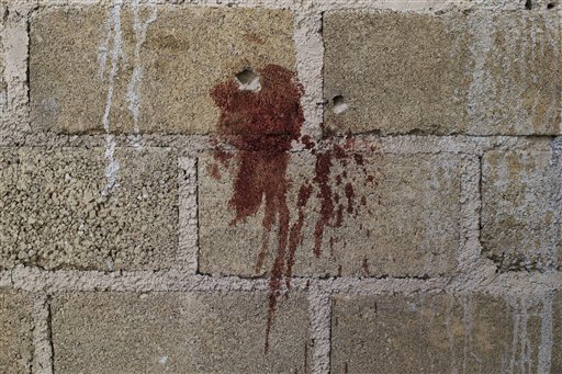 ARCHIVO - En esta imagen del 3 de julio de 2014 se ven orificios de bala y una mancha de sangre en una pared junto a los cadáveres encontrados en un almacén donde hubo un tiroteo entre soldados mexicanos y supuestos delincuentes en las afueras de San Pedro Limón, en el estado de México. (Foto AP/Rebecca Blackwell, Archivo)