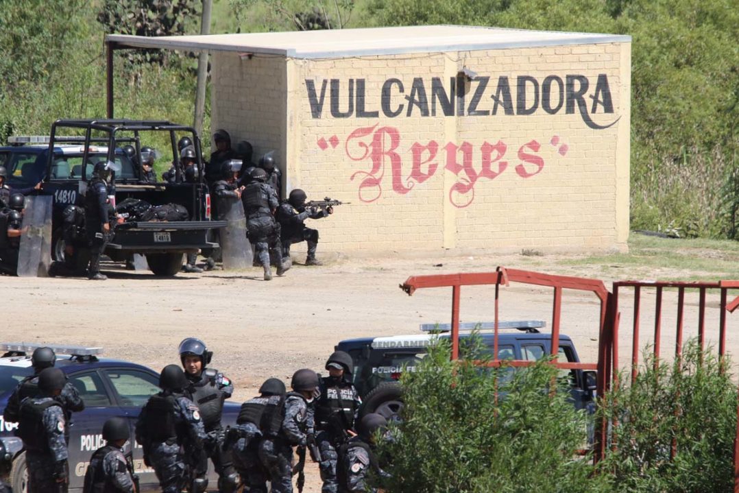 Riot police use a rifle as they battle with protesting teachers who were blocking a federal highway in the state of Oaxaca, near the town of Nochixtlan, Mexico, Sunday, June 19, 2016. The teachers are protesting against plans to overhaul the country's education system which include federally mandated teacher evaluations. (AP Photo/Luis Alberto Cruz Hernandez)